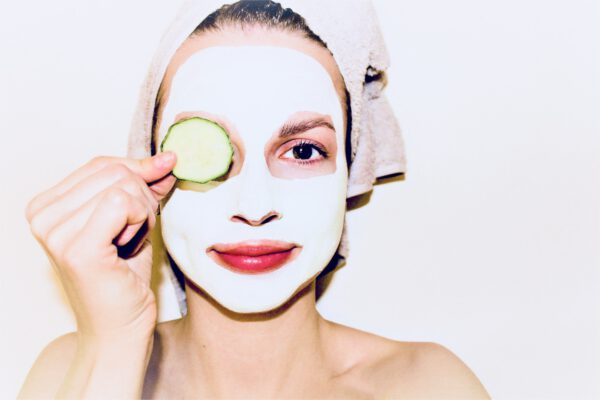 Junge Frau mit Maske und Gurkenscheibe