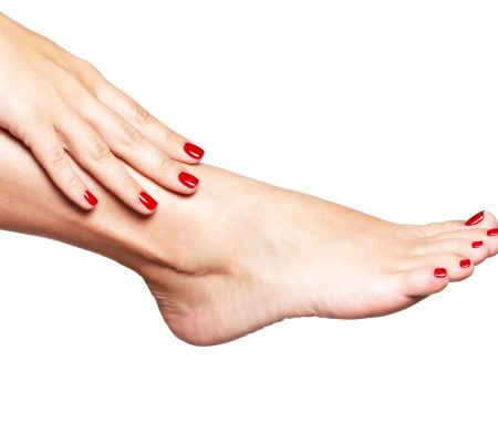 Closeup photo of a female feet with beautiful red pedicure over white background